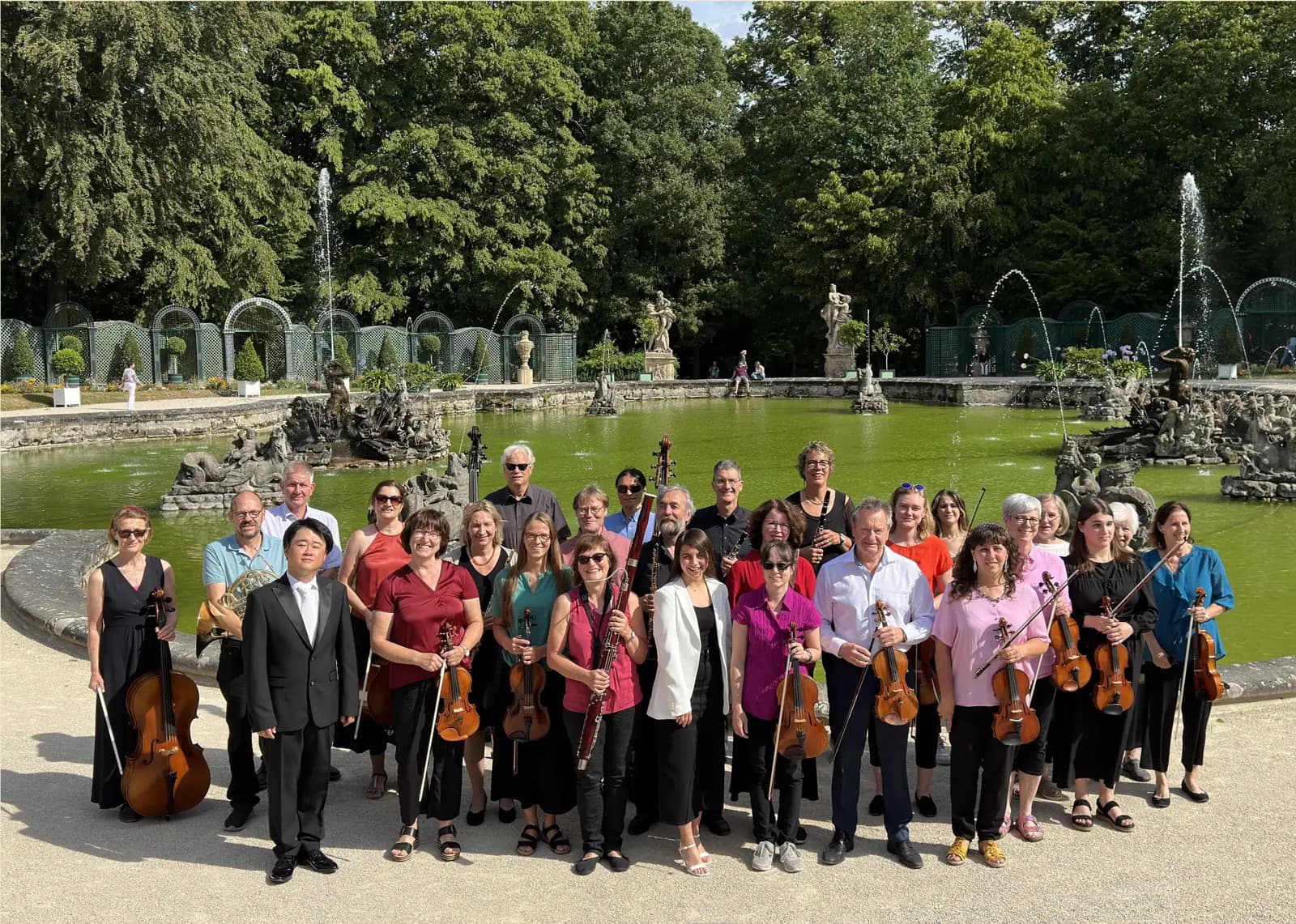 Die Mitglieder des Orchestervereins Bayreuth mit ihren Instrumenten als Gruppe vor dem Wasserbecken der Eremitage.